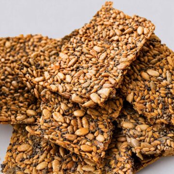 crispy seed crackers stacked close up showing mixed seeds and golden texture
