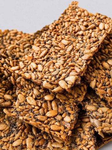 crispy seed crackers stacked close up showing mixed seeds and golden texture