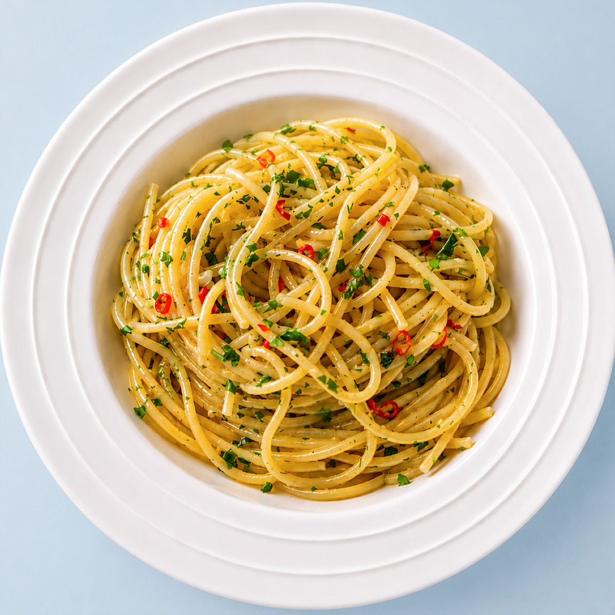 Spaghetti Aglio e Olio served in a white pasta bowl, tossed with garlic olive oil, parsley, and red chili for a classic Italian pasta dish.