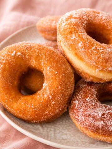 easy sugar donuts on a plate with a soft crumb and crisp golden exterior, dusted with sugar