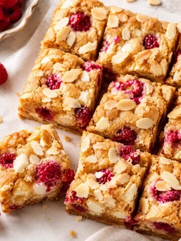 White chocolate raspberry blondies cut into squares with fresh raspberries and sliced almonds