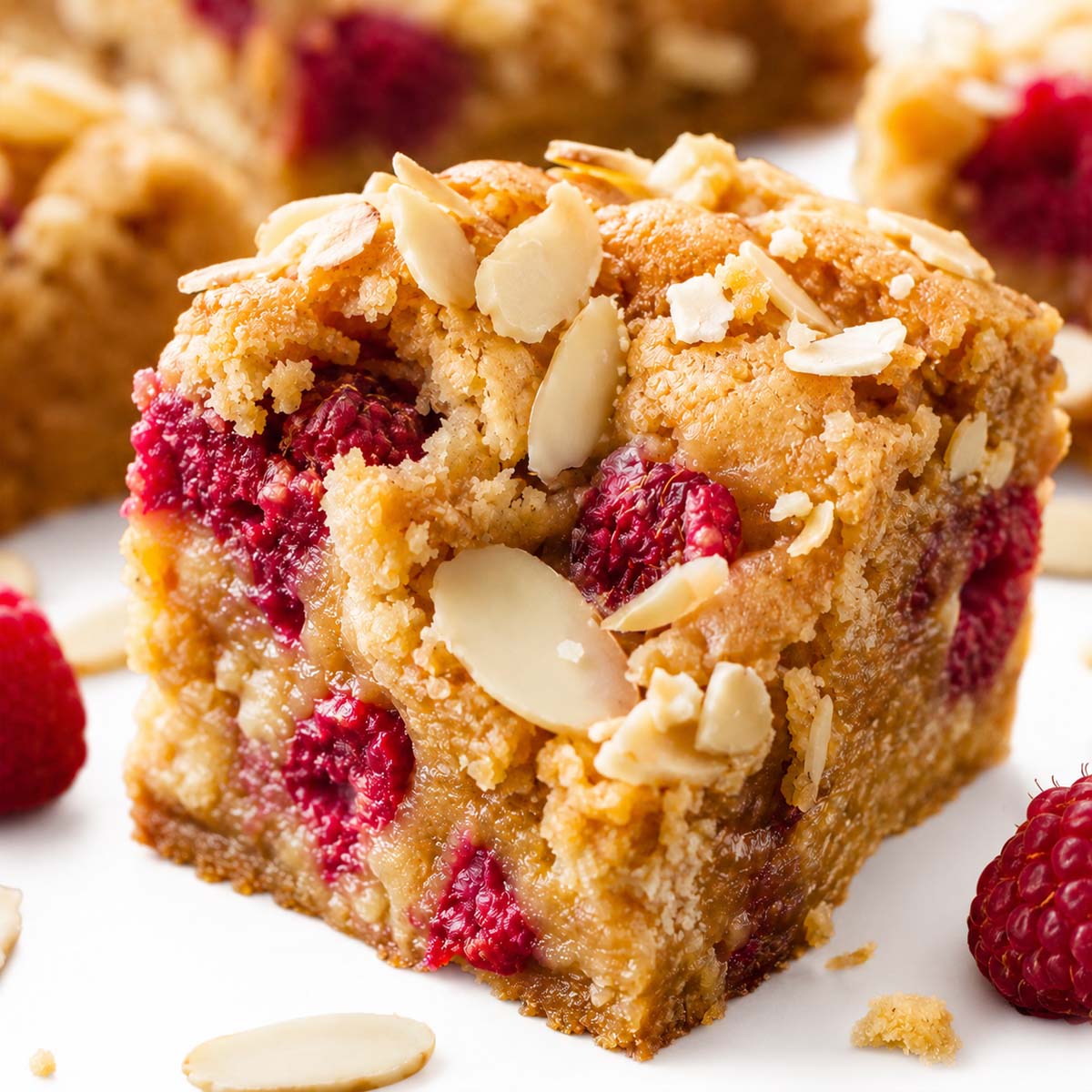Close-up of white chocolate raspberry blondies with juicy raspberries and sliced almonds