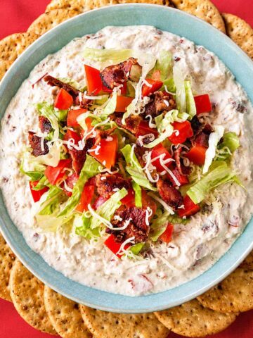 Creamy BLT dip topped with crispy bacon, diced tomatoes, shredded romaine, and cheddar, served with crackers.