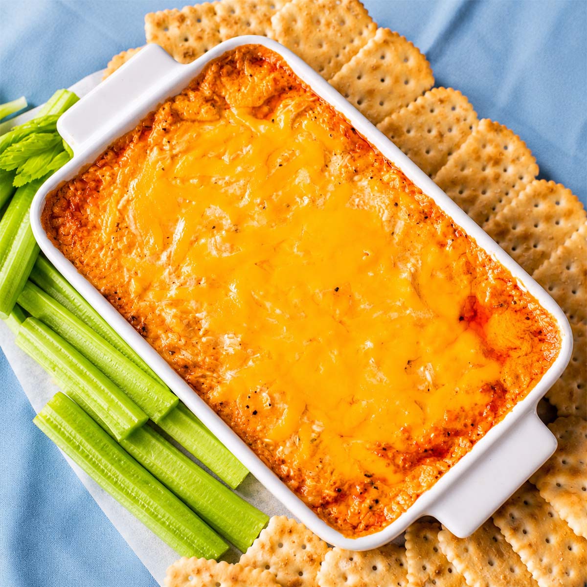 Rotisserie Buffalo Chicken Dip with melted cheddar, crackers, and celery sticks for dipping
