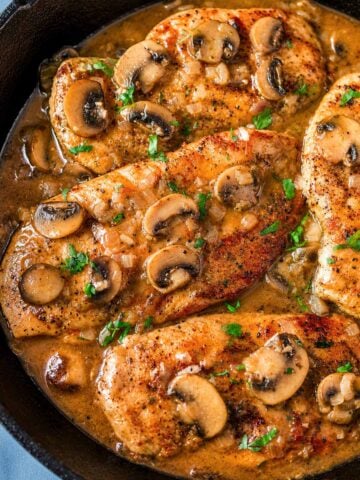 Chicken Marsala without cream in a skillet with sautéed mushrooms, onions, and a glossy Marsala wine sauce, finished with parsley.