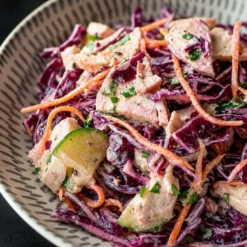 Close up Creamy chicken and cabbage salad with red cabbage, cucumber, carrot, and tender chicken pieces in a light dressing
