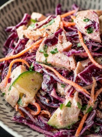 Close up Creamy chicken and cabbage salad with red cabbage, cucumber, carrot, and tender chicken pieces in a light dressing