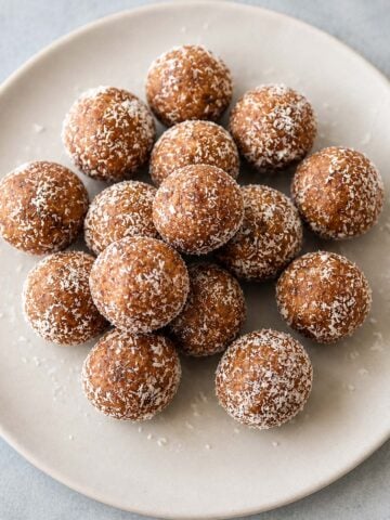 Date and Walnut Energy Balls (Easy No-Bake Snack) dusted with coconut on a white plate.