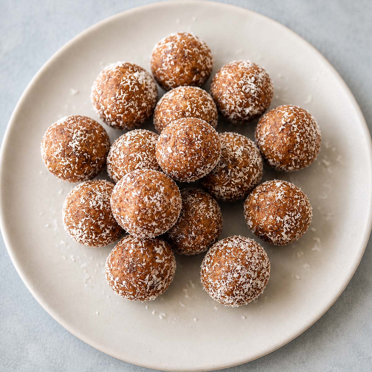 Date and Walnut Energy Balls (Easy No-Bake Snack) dusted with coconut on a white plate.