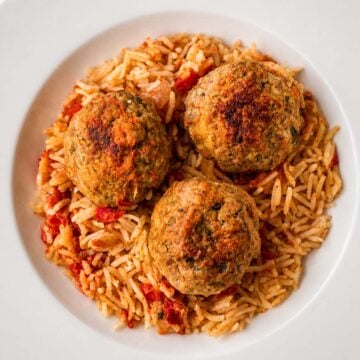 One pan meatballs and rice served in a white bowl, featuring juicy homemade meatballs over seasoned tomato rice
