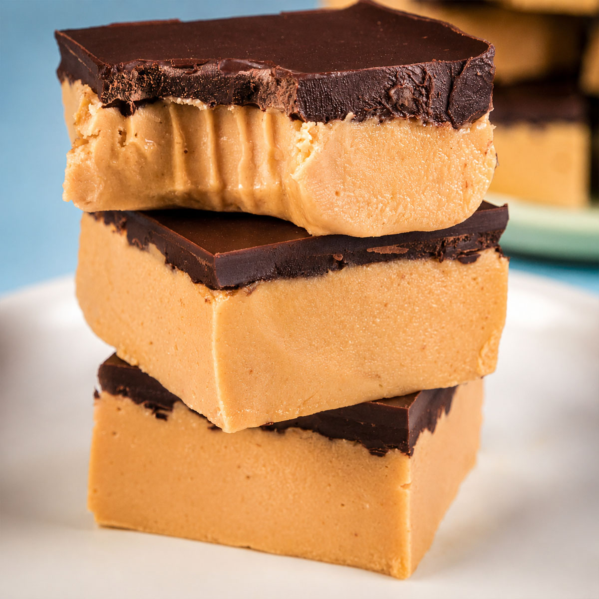 Peanut butter bars with dark chocolate topping, including one bar with a bite showing the creamy filling