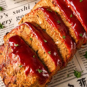 Close-up of sliced turkey meatloaf with a glossy brown sugar ketchup glaze dripping over the cut edges.