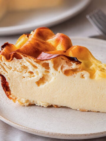Slice of 4-ingredient yogurt cake on a white plate, with a golden-brown top and soft, creamy custard-like center.