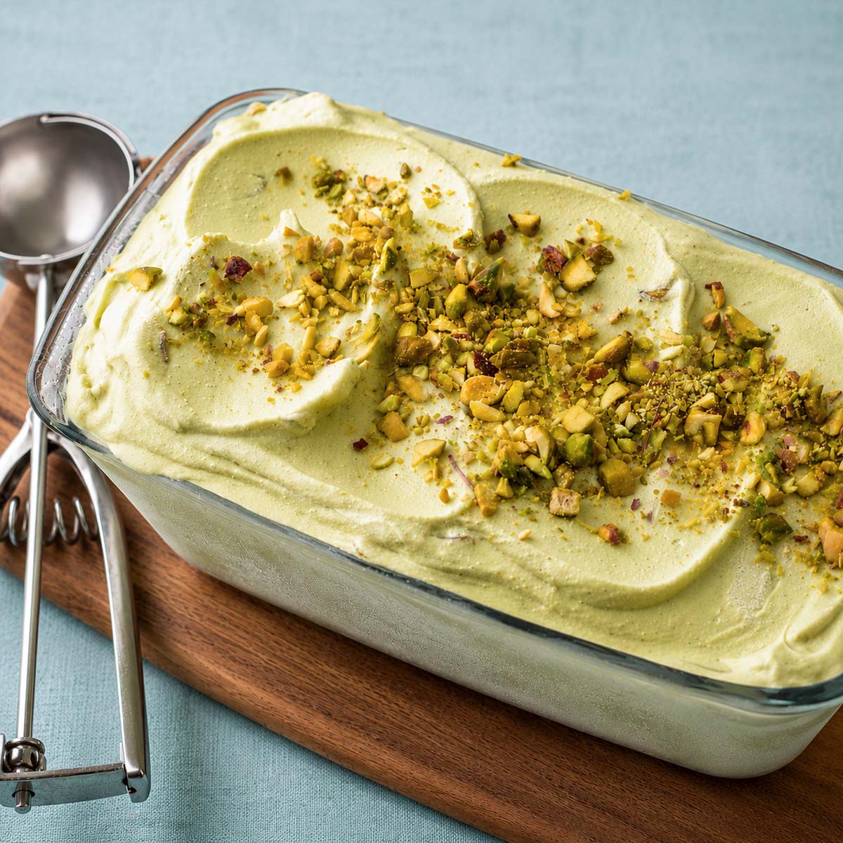 No-churn avocado ice cream topped with chopped pistachios in a loaf pan