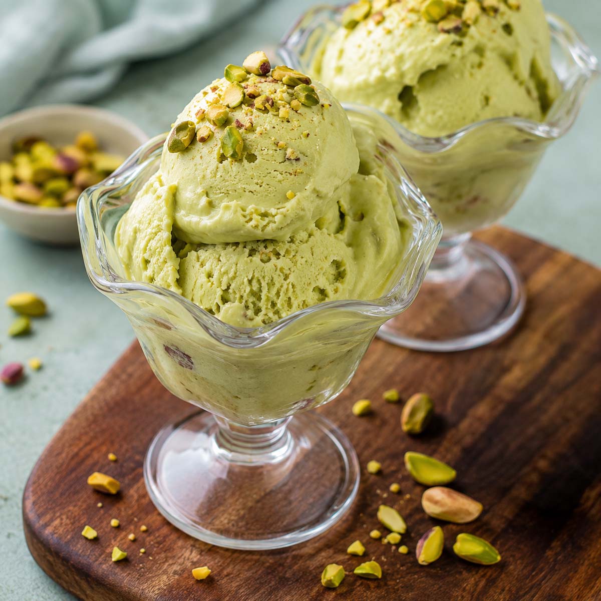 Creamy no-churn avocado ice cream scoops topped with pistachios in a glass dessert dish