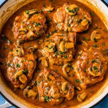 Chicken Chasseur (French hunter's chicken) with golden chicken thighs simmered in a rich mushroom, tomato, and white wine sauce in a skillet.