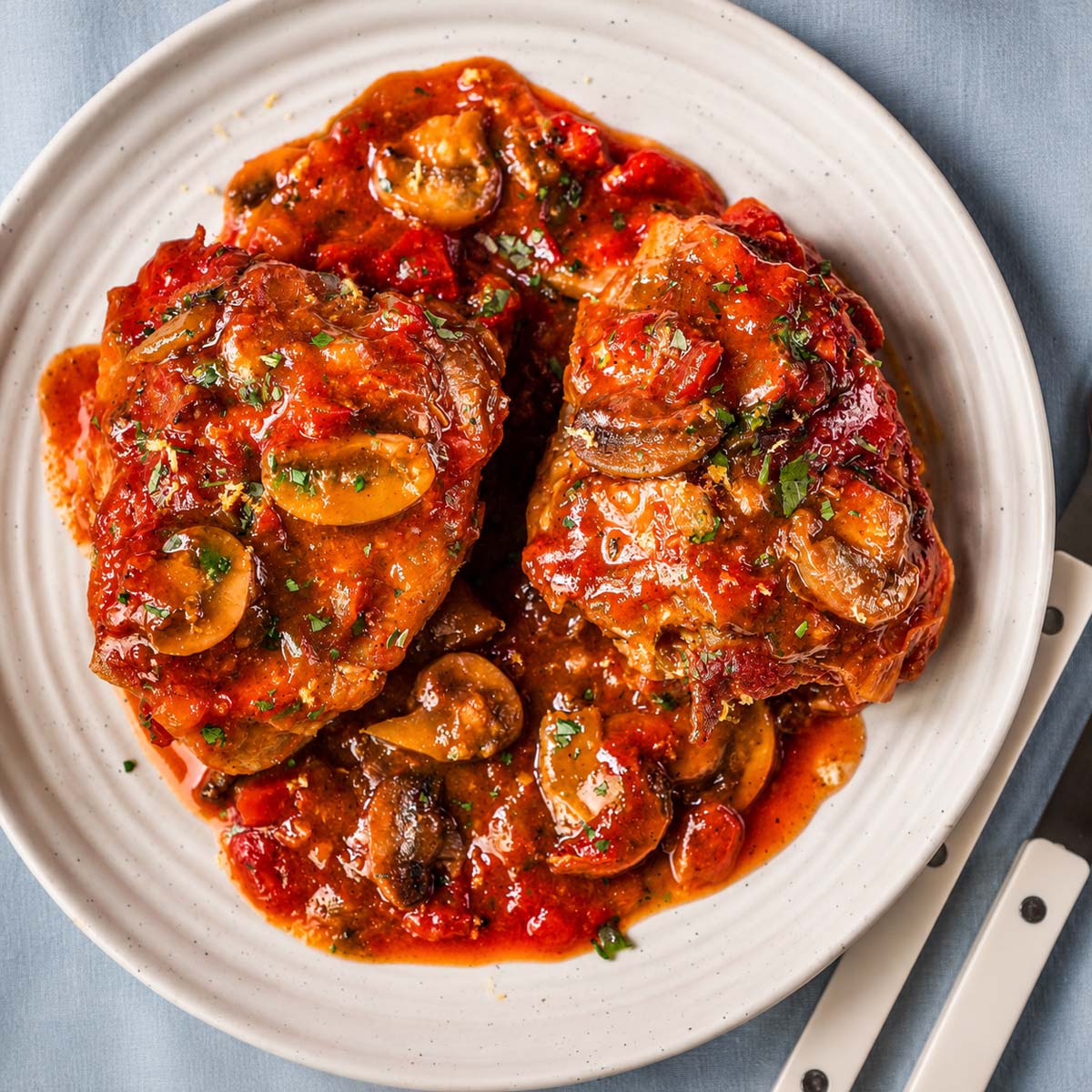 Plated Chicken Marengo with braised chicken thighs, mushrooms, and savory tomato wine sauce