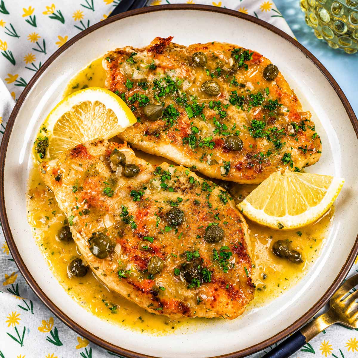 Lemon Chicken Piccata served on a plate with a bright lemon butter caper sauce, garnished with fresh parsley and lemon wedges.