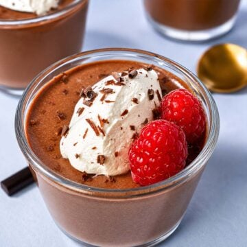 Creamy cottage cheese chocolate mousse topped with whipped cream, fresh raspberries, and chocolate shavings