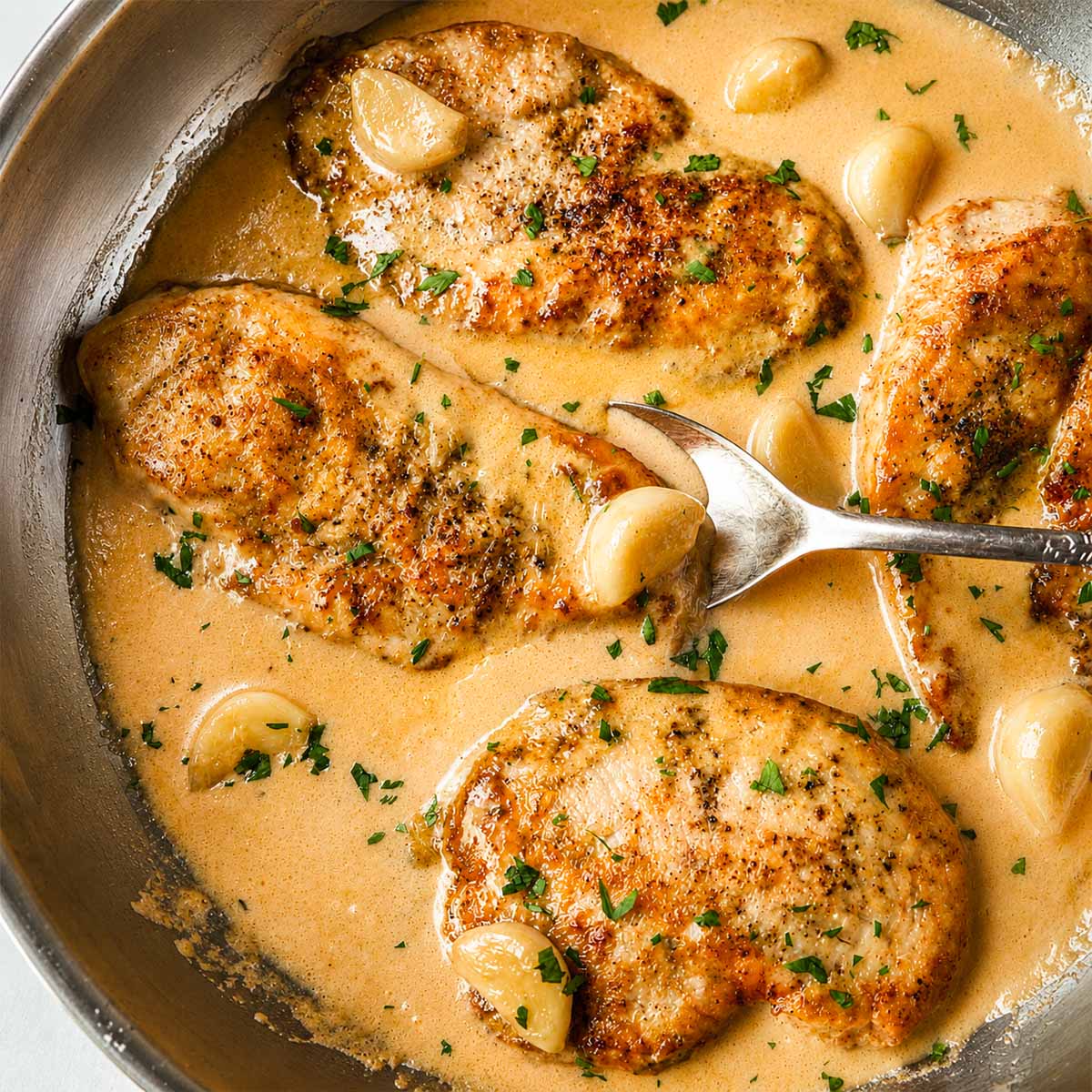 Creamy garlic chicken served on a plate with tender pan-seared chicken breasts, whole garlic cloves, and rich homemade garlic cream sauce.