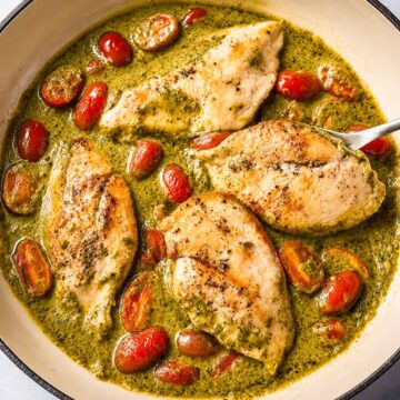 Creamy pesto chicken with cherry tomatoes cooked in a skillet with a rich Parmesan pesto cream sauce