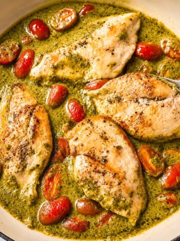 Creamy pesto chicken with cherry tomatoes cooked in a skillet with a rich Parmesan pesto cream sauce