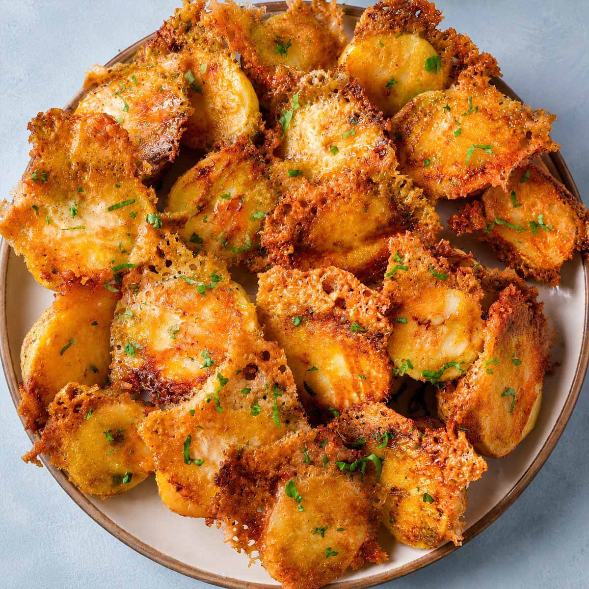 Crispy Parmesan Potatoes with Golden Cheese Crust served on a plate with crispy lacy Parmesan edges and fresh parsley