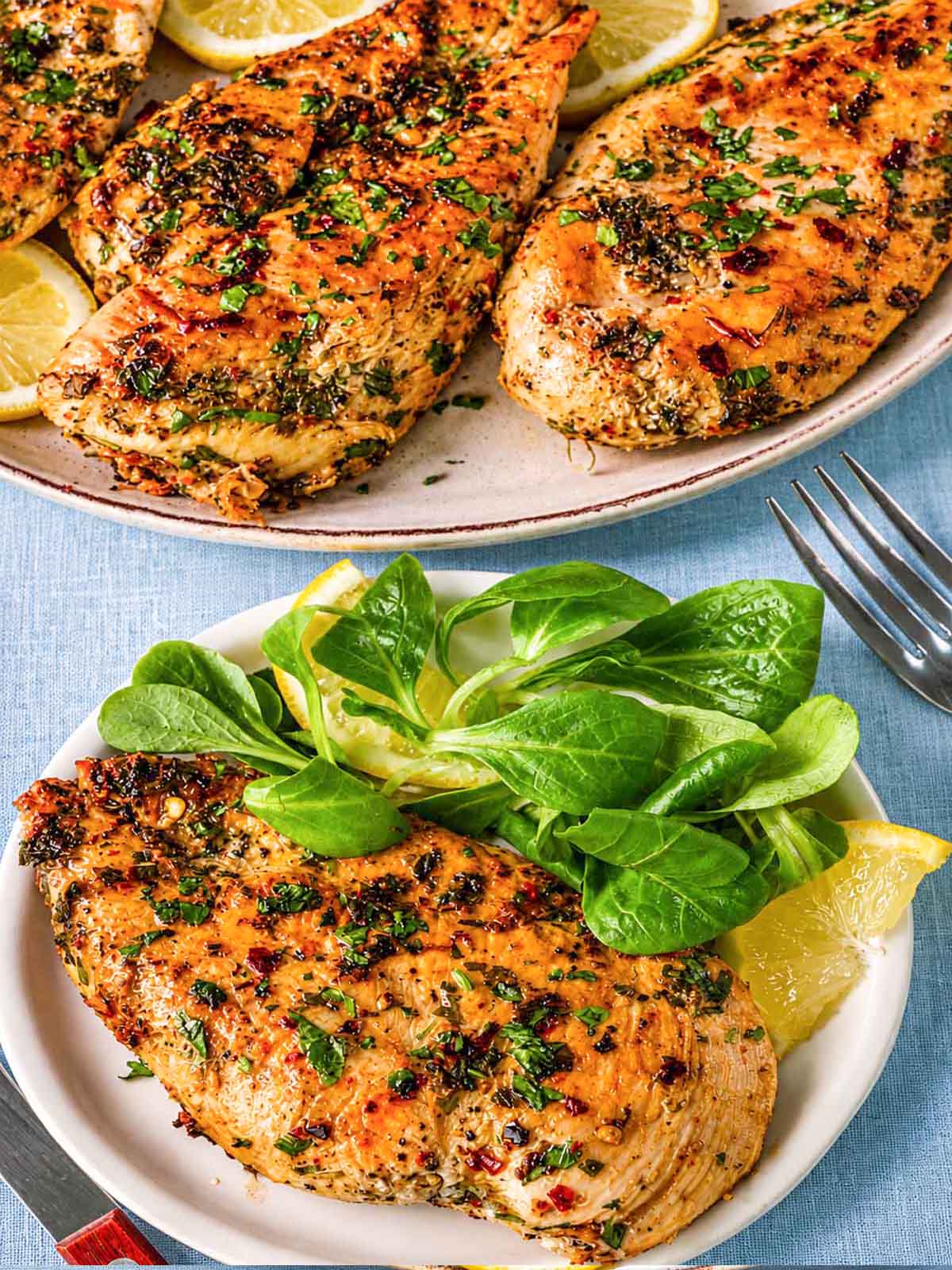 Plated Greek lemon chicken cutlets with a golden sear, served with fresh green salad on the side.