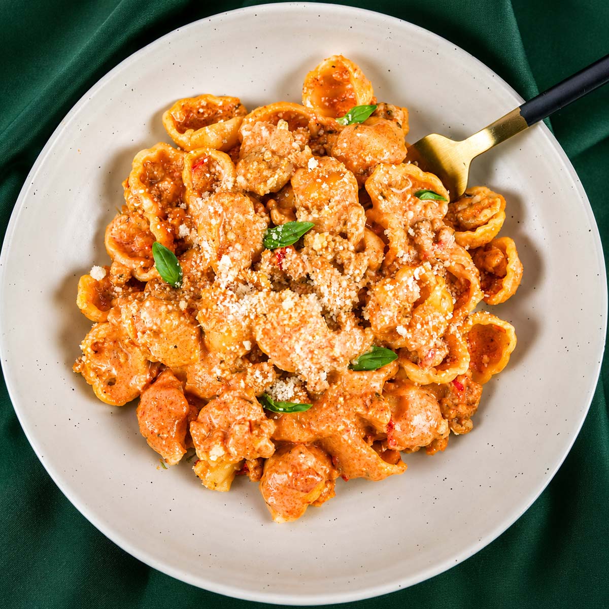Creamy ground turkey pasta shells in tomato sauce served on a white plate, topped with grated Parmesan and basil, with a fork on the side.