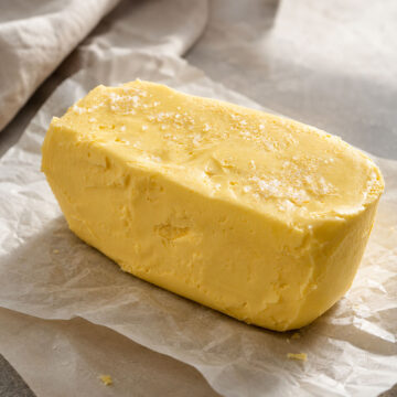 Creamy homemade butter from heavy cream on parchment paper in a bright editorial-style kitchen scene with coarse sea salt
