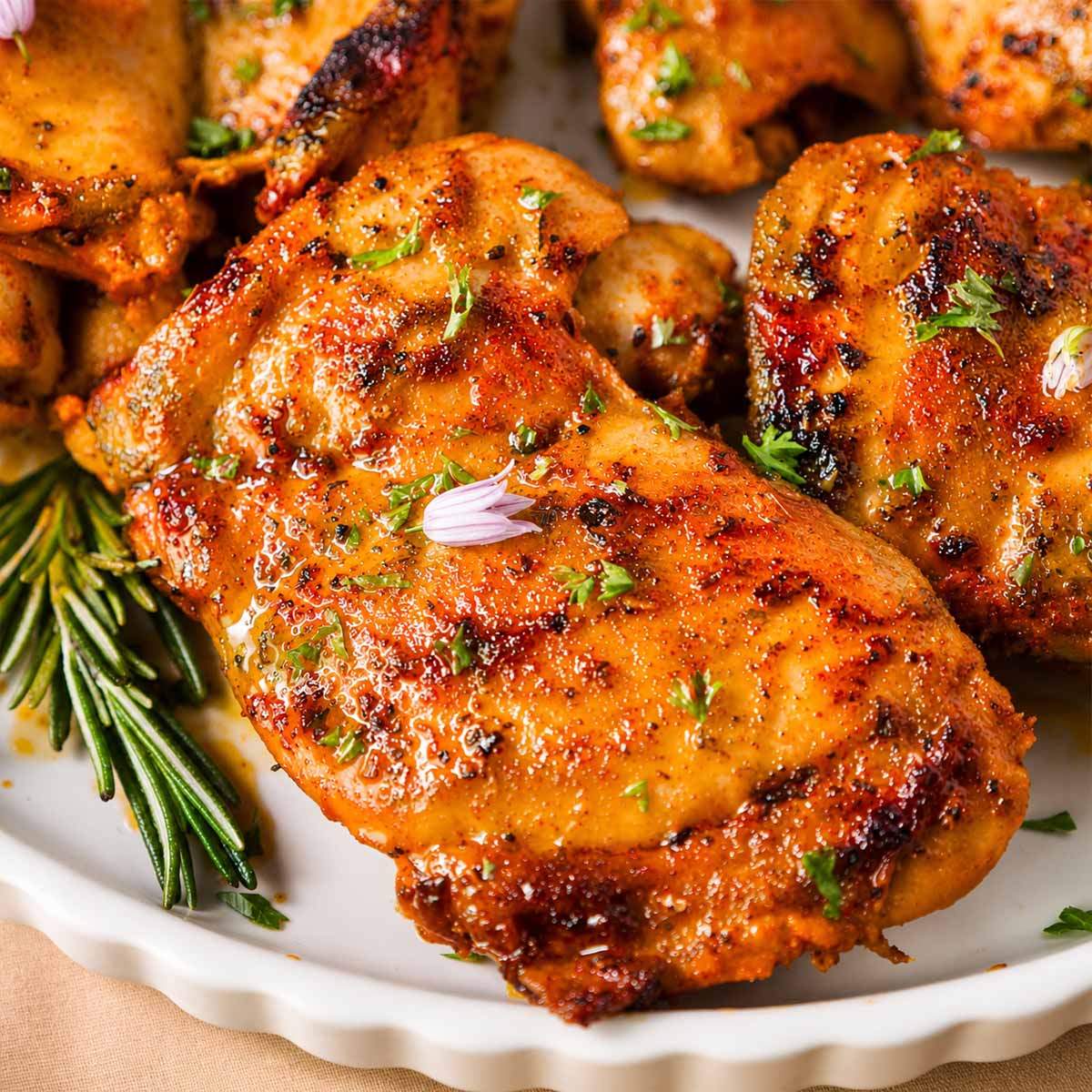 Close-up of Italian chicken thigh with garlic and lemon, seared golden and garnished with fresh herbs on a plate.