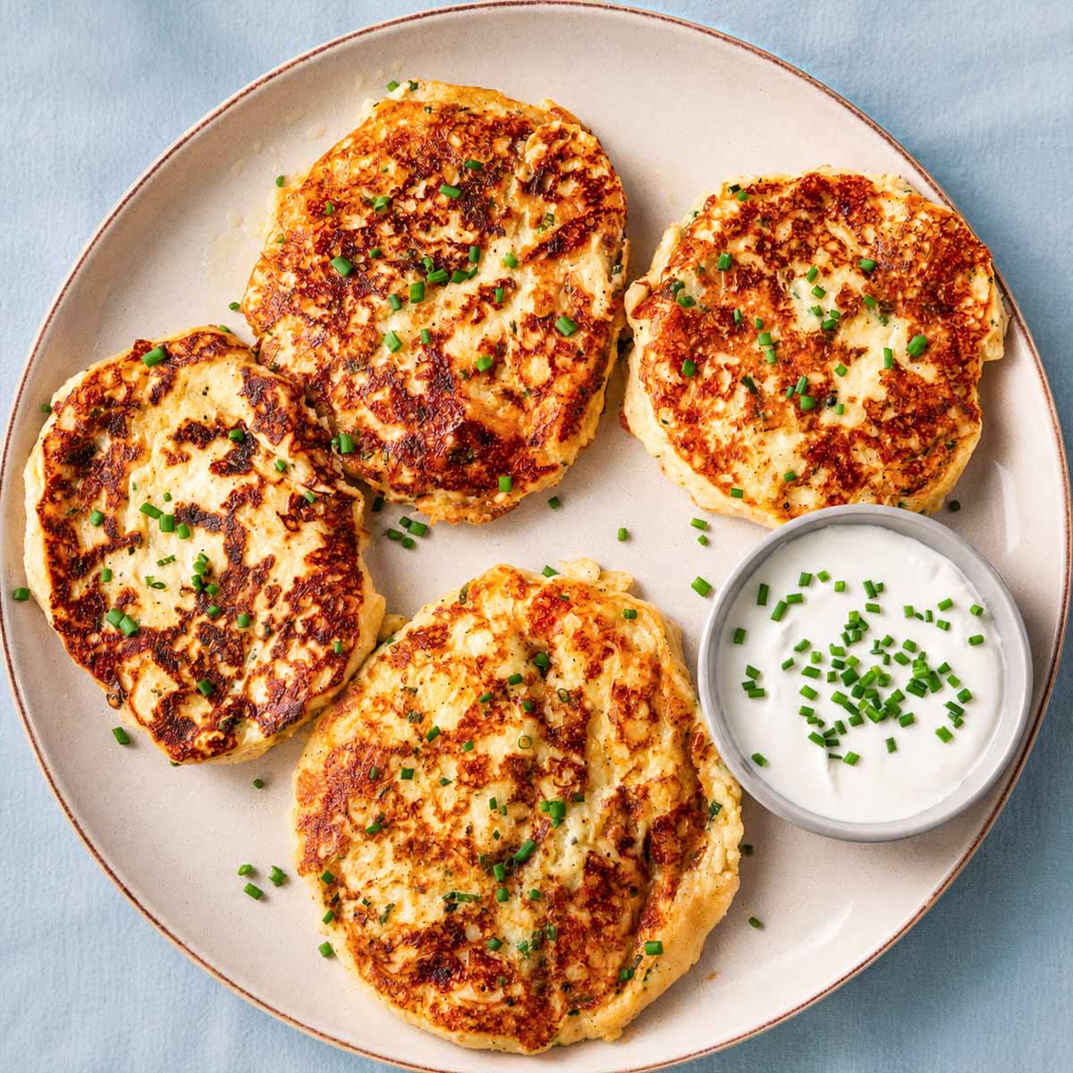 Crispy leftover mashed potato pancakes served with sour cream and fresh chives on a plate