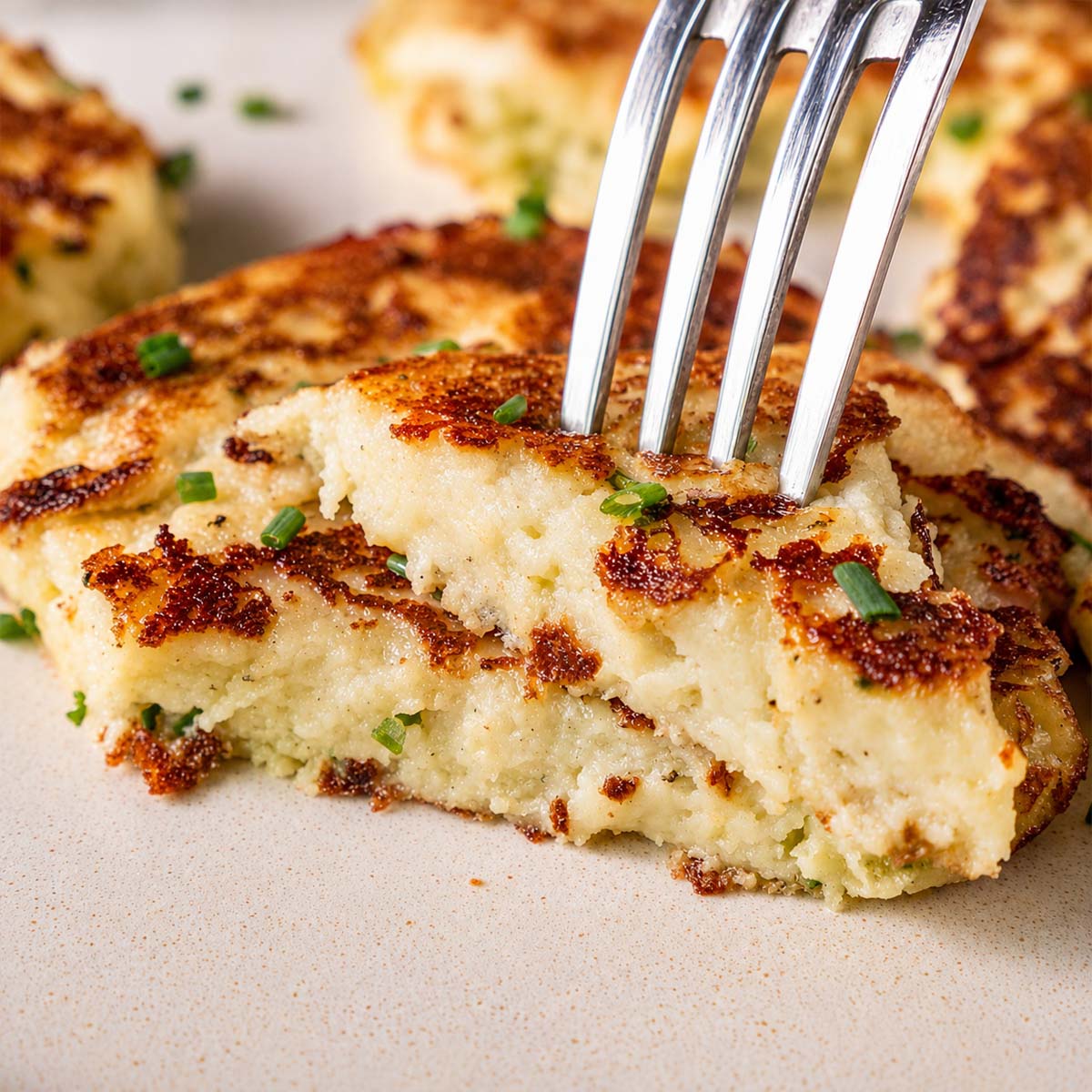 Fork cutting into a crispy leftover mashed potato pancake showing the soft fluffy center