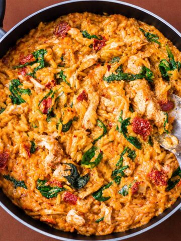 Creamy Marry Me chicken orzo with spinach and sun-dried tomatoes in a skillet