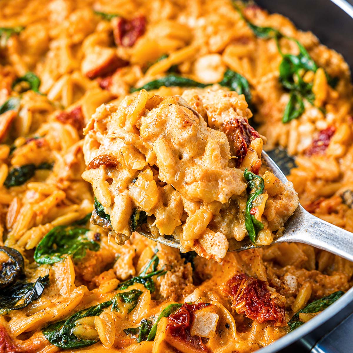 Spoonful of creamy Marry Me chicken orzo with spinach and sun-dried tomatoes