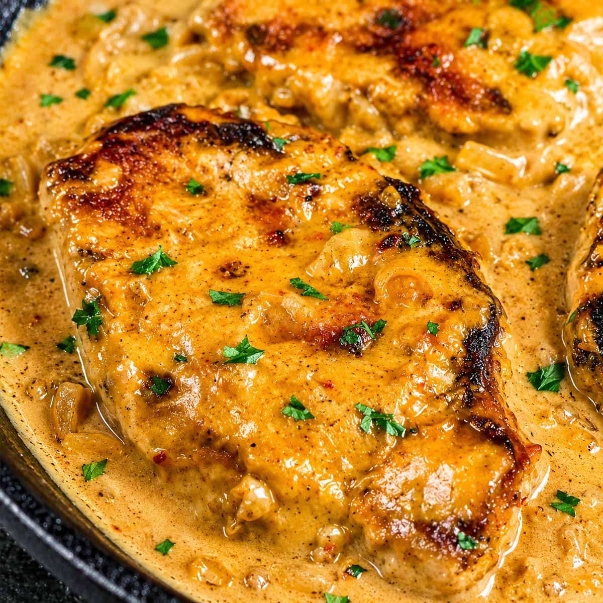 Juicy smothered pork chops with creamy onion gravy and tender onions in one skillet