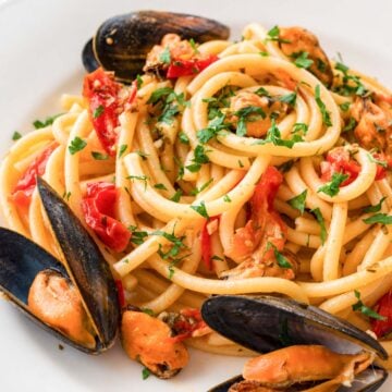 Spaghetti with mussels tossed with cherry tomatoes, garlic, parsley, and chilli in a light Italian seafood pasta sauce.