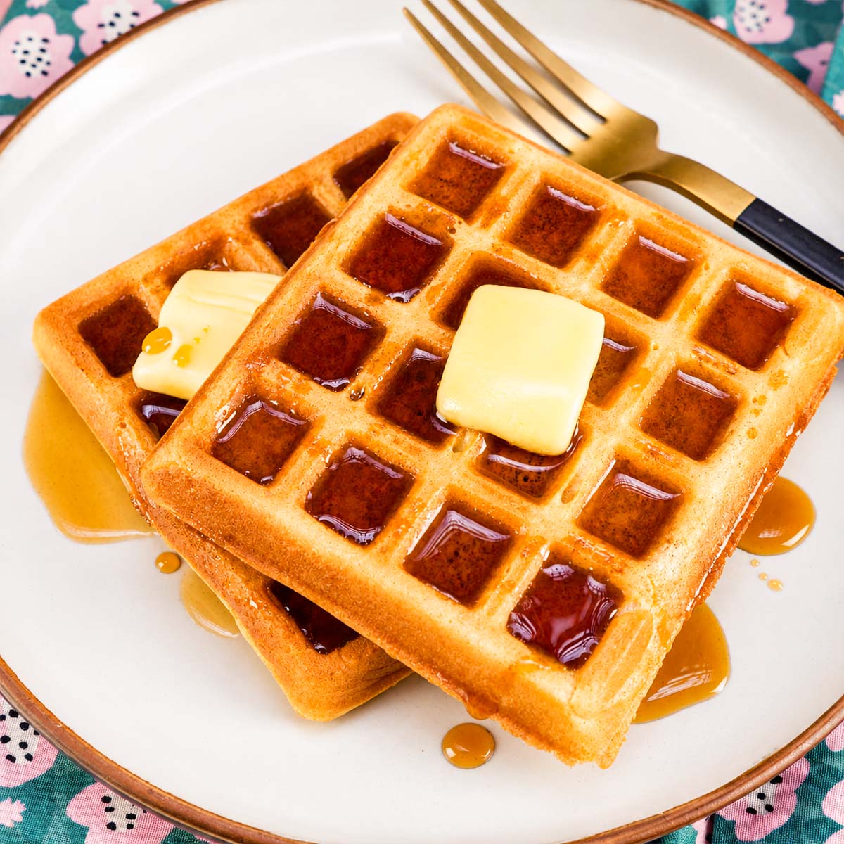 Homemade waffles topped with butter and maple syrup on a plate