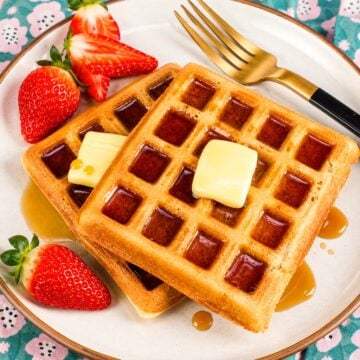 Golden homemade waffles with butter, maple syrup, and fresh strawberries