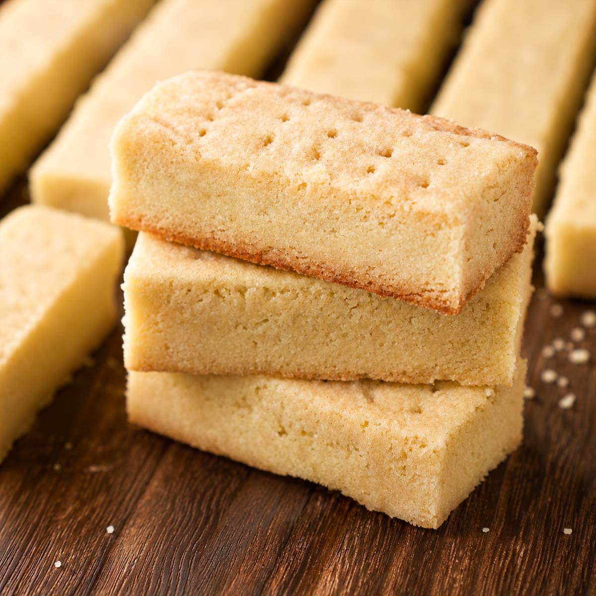 Traditional shortbread cookies stacked on a wooden board showing their buttery texture and tender crumb