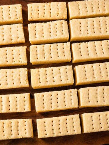 Traditional shortbread cookies arranged on a wooden board showing thick buttery biscuit fingers ready to serve