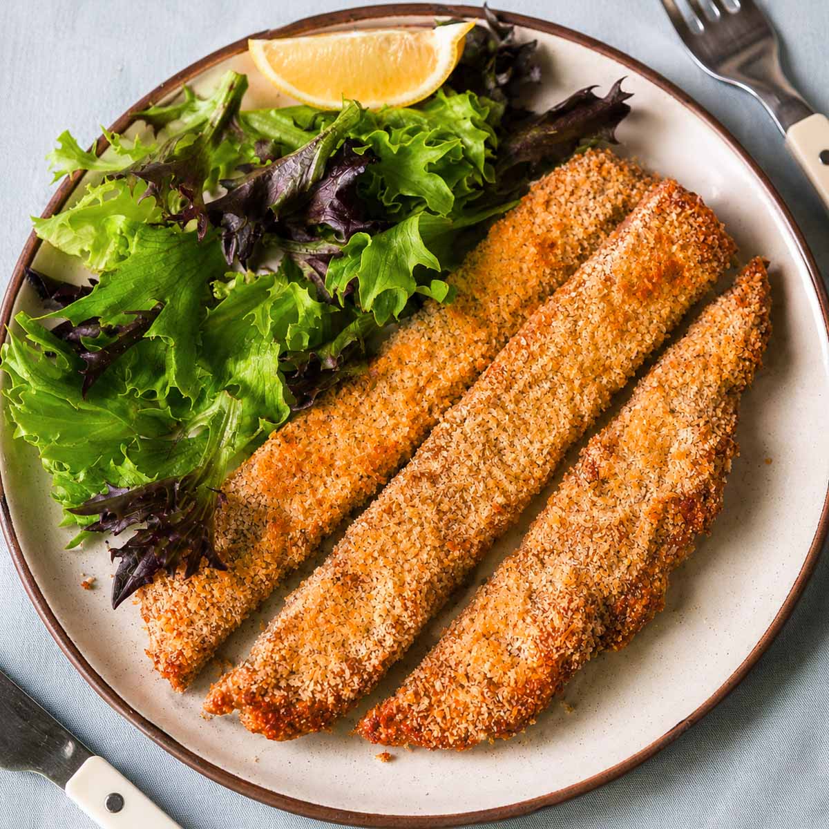 4 ingredient ground chicken cutlets served with mixed green salad and a lemon wedge.