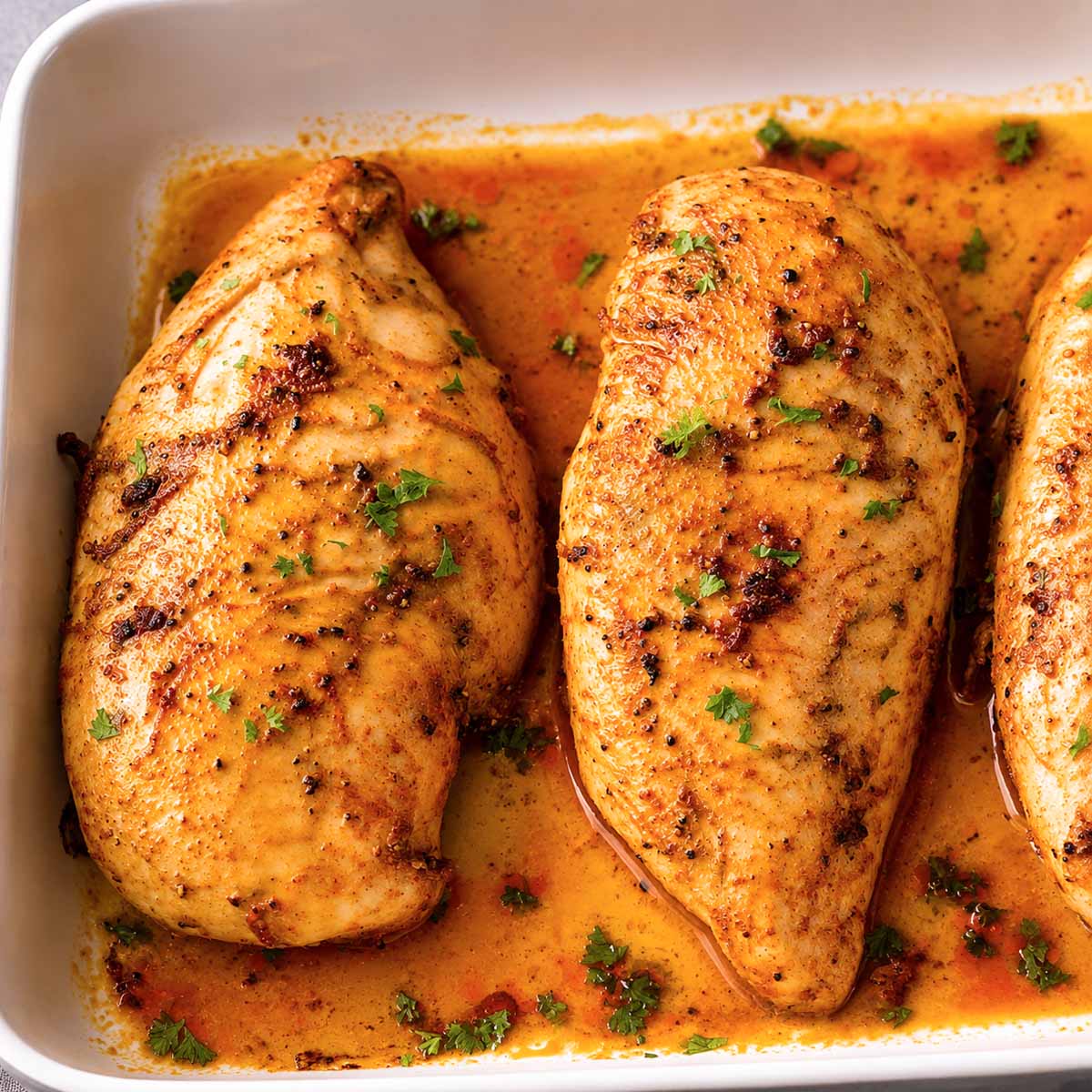 Oven baked chicken breasts with golden seasoning and pan juices