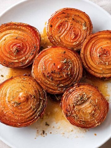 Balsamic roasted onions served on a white plate with caramelized layers and rosemary.