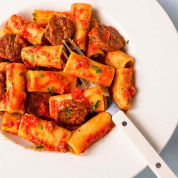 Fork lifting chorizo from Spanish chorizo pasta with tomato sauce