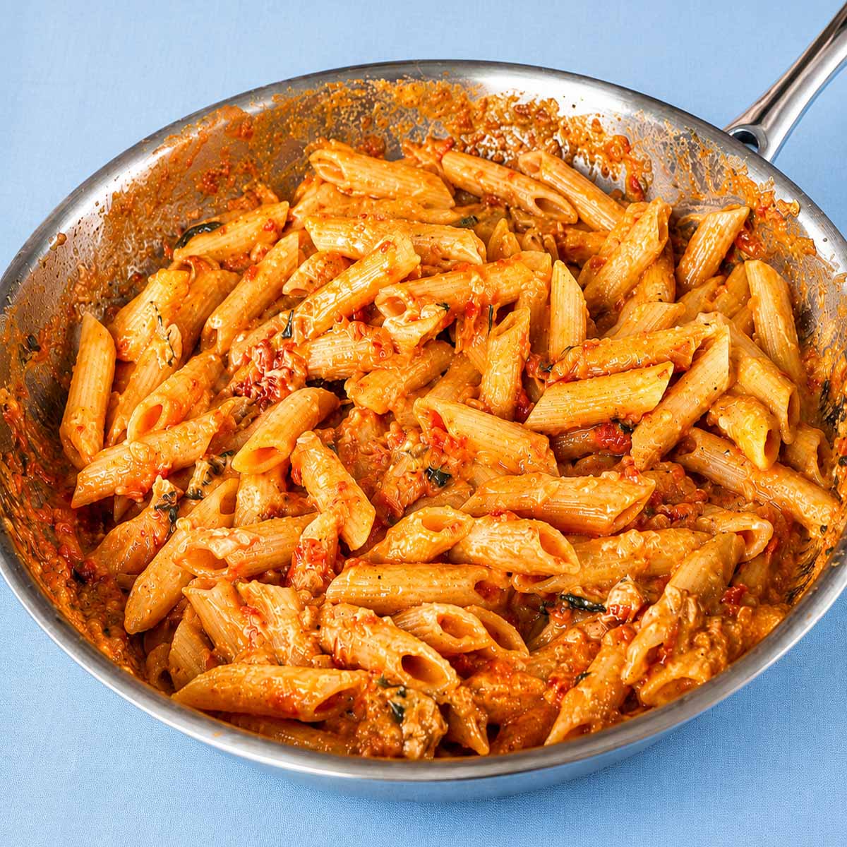 Creamy tomato penne pasta in a skillet with Parmesan cheese