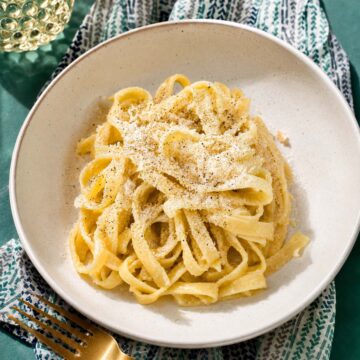Fettuccine al burro in a white bowl, coated in a creamy butter sauce and topped with grated Parmesan.