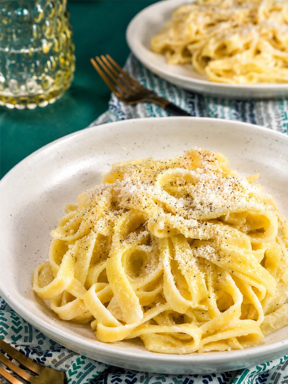 Creamy fettuccine al burro in a white bowl topped with grated Parmesan.