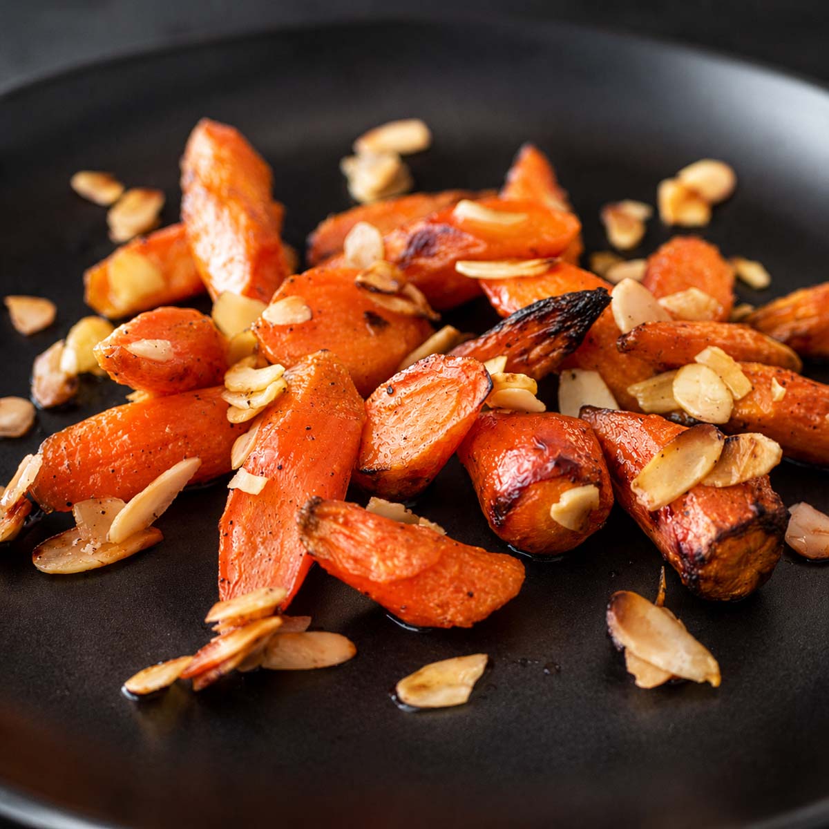 Close-up of honey roasted carrots with almonds showing caramelized roasted carrots with honey glaze and toasted almond slices.