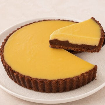 Chocolate orange tart with one slice lifted on a cake server, revealing its three distinct layers.